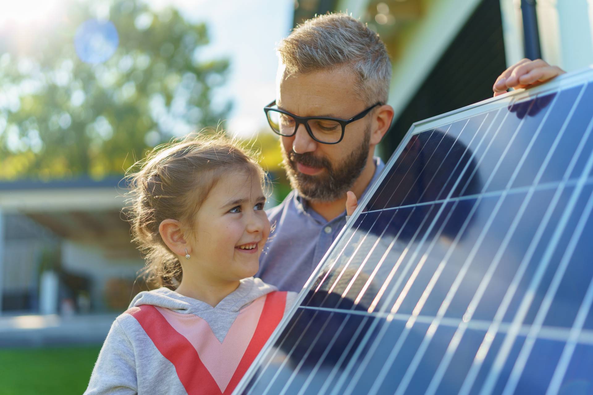 Hombre enseña una placa solar a su hija